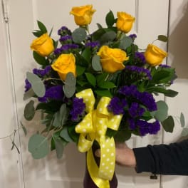 Bouquet of yellow roses and purple filler flowers with a yellow polka-dot ribbon