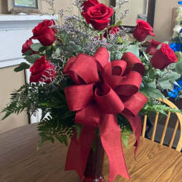 Red roses in a glass vase with a large red ribbon bow
