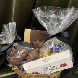 Gift basket with chocolate truffles and boxed candies wrapped in clear cellophane
