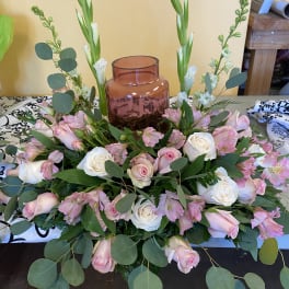 Pink and white rose arrangement with tall green stems in a glass vase