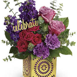 Mixed pink, purple, and red roses in a decorative yellow box with a "celebrate" sign