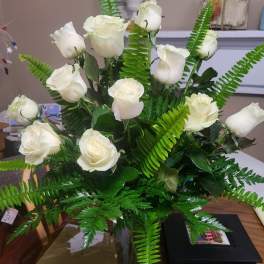 White roses arranged with fern foliage in a clear vase