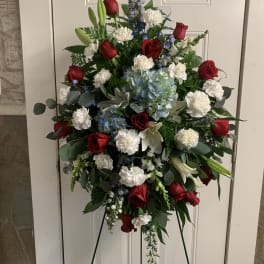 Standing floral spray with red roses, white carnations, and blue flowers