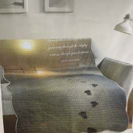 Printed blanket on a sofa with a sunset scene and Bible verse