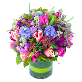 Colorful bouquet of mixed flowers in a green glass vase