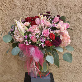 Pink and red rose bouquet with lilies in a glass vase