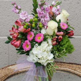 Mixed pink and white bouquet in a glass vase with a lavender ribbon