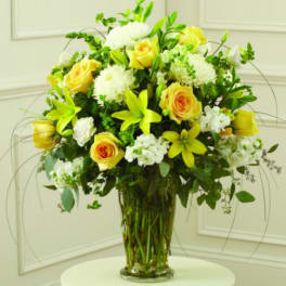 Yellow roses and white flowers arranged in a clear glass vase