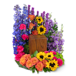 Colorful floral wreath with sunflowers, roses, and purple blooms around a wooden urn