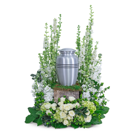 White floral funeral urn arrangement with a silver urn centerpiece