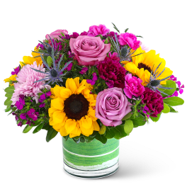 Mixed bouquet with sunflowers, pink roses, and carnations in a glass vase