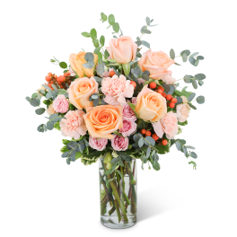 Peach and pink roses in a clear glass vase