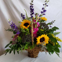 Basket arrangement with sunflowers, purple blooms, and pink flowers