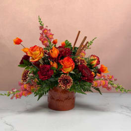 Mixed orange, pink, and burgundy flowers in a brown vase