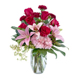 Bouquet of red roses and pink lilies in a clear glass vase