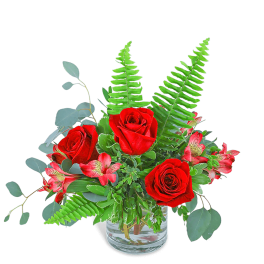 Red roses and pink flowers in a clear glass vase
