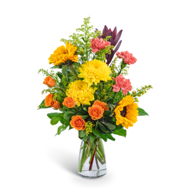 Bouquet of yellow sunflowers, orange roses, and pink carnations in a clear glass vase
