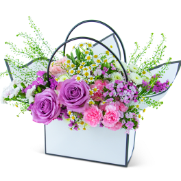 Bouquet of purple roses and pink mixed flowers in a white handled box