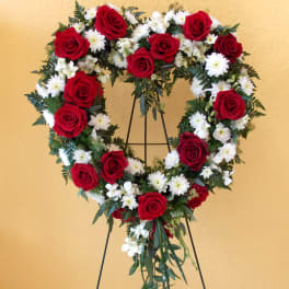 Heart-shaped wreath of red roses and white daisies on a stand