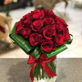 Bouquet of red roses in a glass vase with a red ribbon