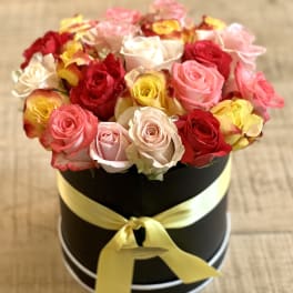 Round box of multicolored roses tied with a yellow ribbon