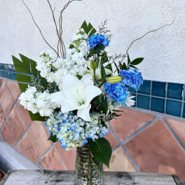 White lilies and blue carnations in a glass vase