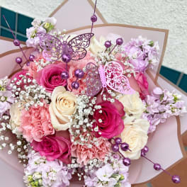 Pink and cream rose bouquet with lilac flowers and butterfly picks