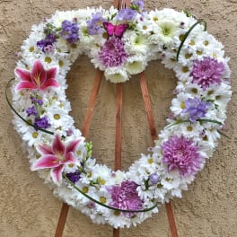 Heart-shaped floral wreath with white daisies, pink lilies, and purple blooms