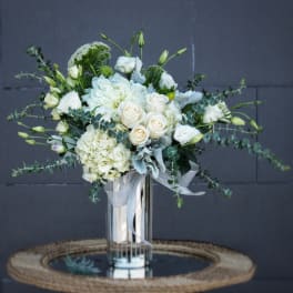 White floral arrangement in a tall glass vase with ribbon