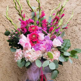 Pink and lavender bouquet in a glass vase with tulle ribbon