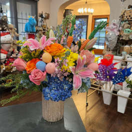 Colorful bouquet with lilies, roses, hydrangeas, and decorative eggs in a glittery vase