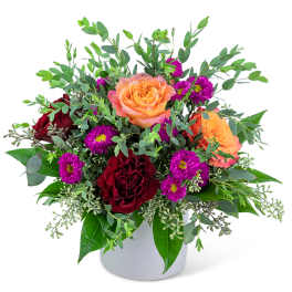 Bouquet of orange and red roses with purple daisies in a white vase