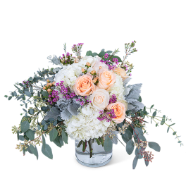 Peach roses and white hydrangeas in a clear glass vase