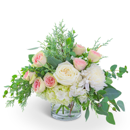 Bouquet of blush and white roses in a clear glass vase