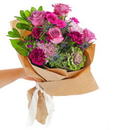 Hand-tied bouquet of pink and purple flowers wrapped in brown paper