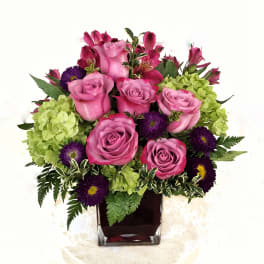 Pink roses and purple flowers in a square glass vase