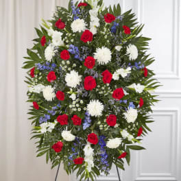 Standing floral spray with red roses, white blooms, and blue accents