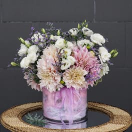 Pink and white flower arrangement in a glass vase with a ribbon