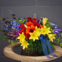 Colorful bouquet of roses, lilies, and daisies in a woven basket