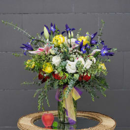 Mixed bouquet of yellow, white, pink, and purple flowers in a glass vase
