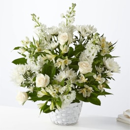 White roses and mixed white flowers in a white basket vase
