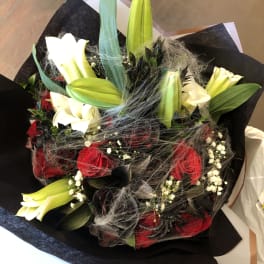 Bouquet of red roses and white lilies wrapped in black paper