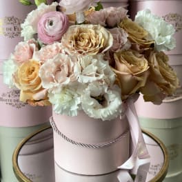 Pastel roses and carnations arranged in a pink hat box