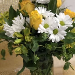 Yellow roses and white daisies in a clear glass vase