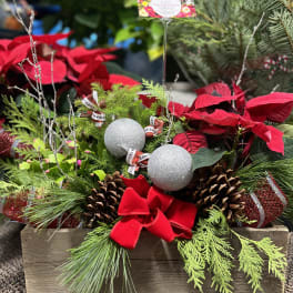 Holiday planter with poinsettias, pinecones, and silver ornaments in a wooden box