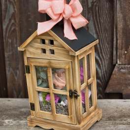 Wooden lantern with pink flowers inside and a pink bow on top