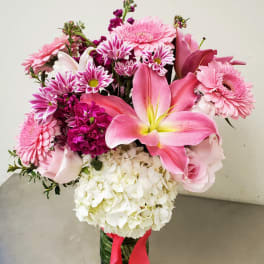 Pink mixed bouquet with lilies, roses, daisies, and white hydrangea in a glass vase