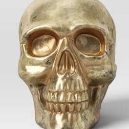 Gold skull decorative object on a plain background