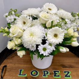 White flowers arranged in a white vase on a wooden tray