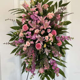 Large pink floral standing spray with roses and lilies on an easel
